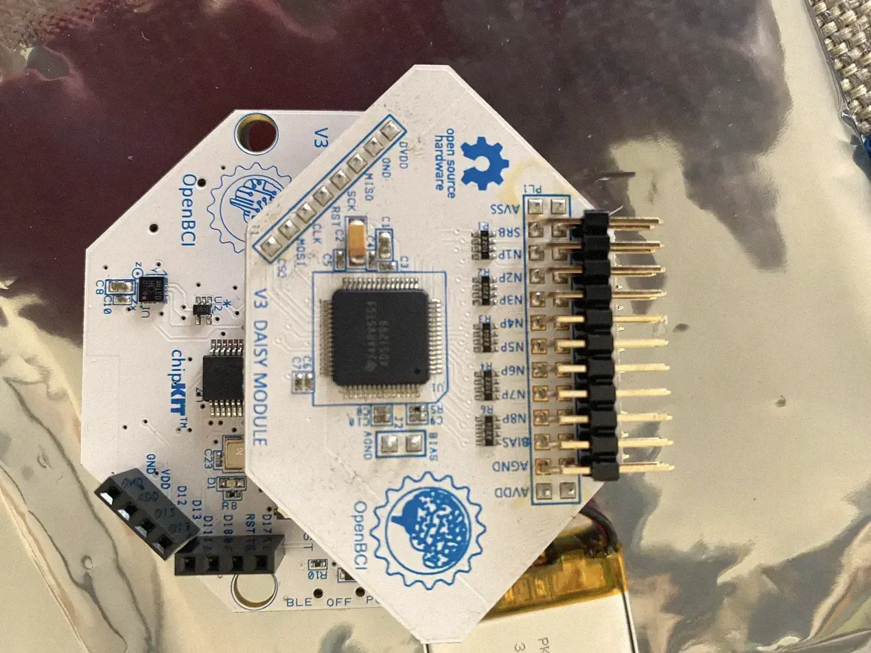 Two stacked OpenBCI circuit boards on a reflective anti-static bag