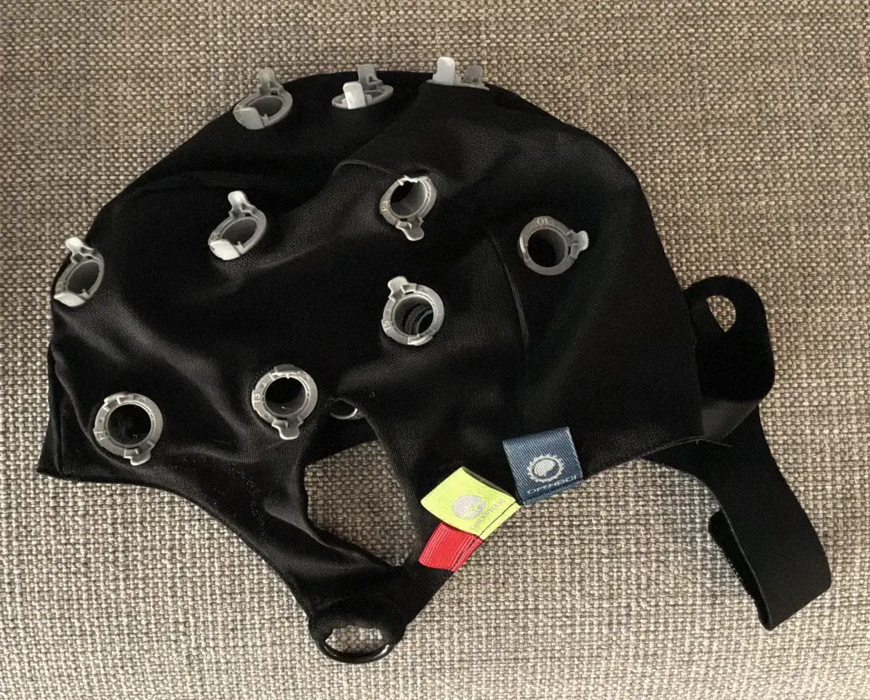 A black EEG cap with grey sensor holders